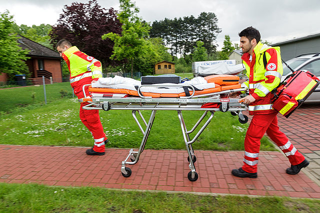 Auf dem Bild sind zwei Mitarbeiter aus dem Rettungsdienst zu sehen.