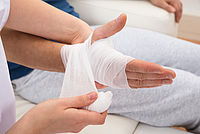 Es wird eine Hand nach einer Verletzung verbunden.