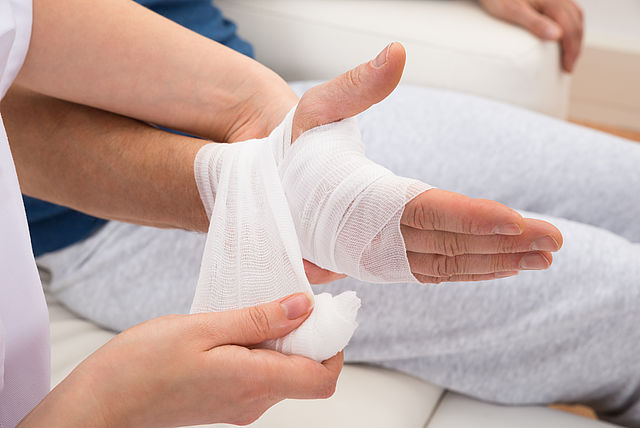 Es wird eine Hand nach einer Verletzung verbunden.